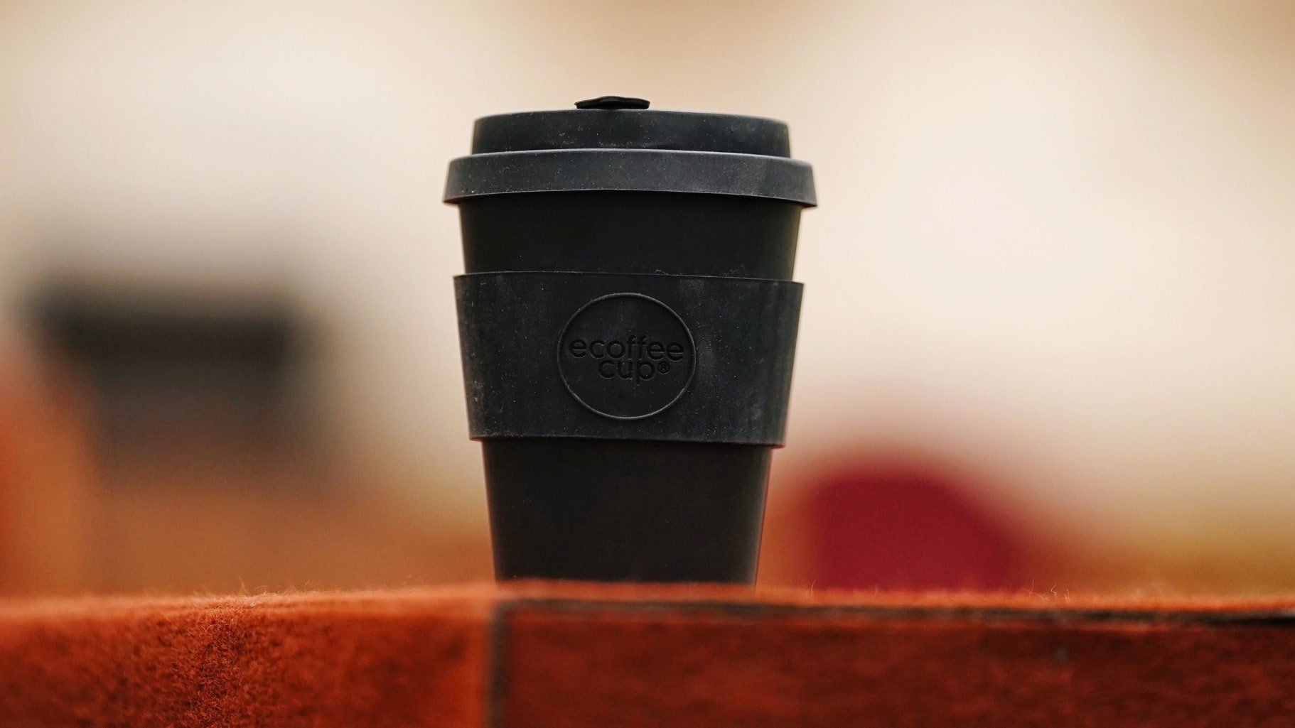 Black reusable Ecoffee cup on a red brick wall