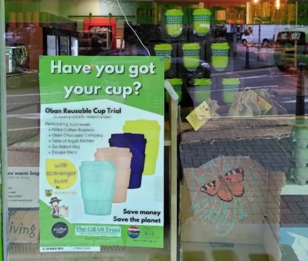 Poster advertising reusable cups in a cafe window in Oban, Scotland